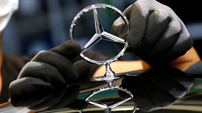 An employee attaches a Mercedes emblem to a Mercedes-Benz S-class car, Sindelfingen, Germany, April 30, 2020.