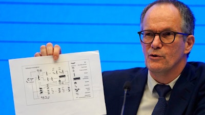 Peter Ben Embarek of the World Health Organization holds up a chart showing pathways of transmission of the virus during a press conference in Wuhan, Feb. 9, 2021.