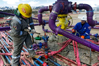Workers tend to a well head during a hydraulic fracturing operation outside Rifle, Colo., March 29, 2013.
