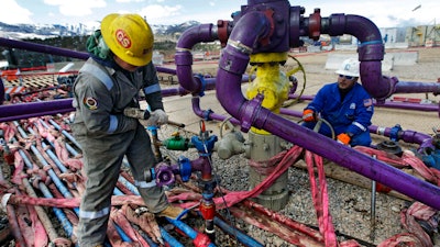Workers tend to a well head during a hydraulic fracturing operation outside Rifle, Colo., March 29, 2013.