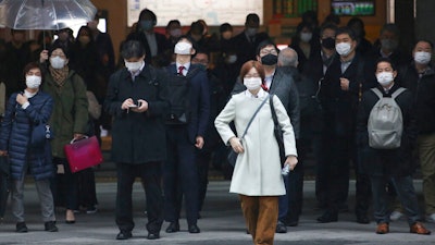 People wait at a crossing in Tokyo, Feb. 15, 2021.