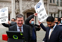 Uber drivers of the ADCU, App Drivers & Couriers Union, celebrate as they listen to the court decision on a tablet outside the Supreme Court in London, Feb. 19, 2021.