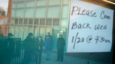 People waiting in line are reflected in the windows of a vaccination site in Paterson, N.J., Jan. 19, 2021.