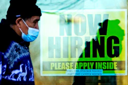 A shopper walks past a store displaying a hiring sign in Wheeling, Ill., Nov. 28, 2020.