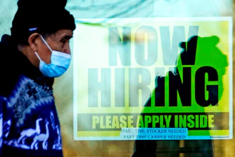 A shopper walks past a store displaying a hiring sign in Wheeling, Ill., Nov. 28, 2020.