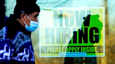 A shopper walks past a store displaying a hiring sign in Wheeling, Ill., Nov. 28, 2020.