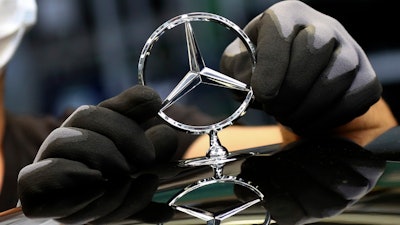 In this file photo, an employee attaches a Mercedes emblem as he works on a Mercedes-Benz S-class car at the Mercedes plant in Sindelfingen, Germany.