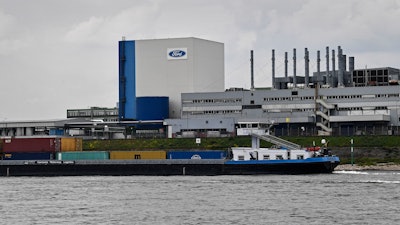 In this file photo, a container ship passes the Ford car plant in Cologne, Germany.