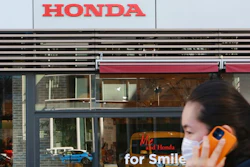 A woman wearing a face mask walks in front of a Honda Motor Co. showroom in Tokyo, Tuesday, Feb. 9, 2021. Japanese automaker Honda reported Tuesday its fiscal third quarter profit more than doubled to 284 billion yen ($2.7 billion) despite the coronavirus pandemic as auto sales grew in Japan and the U.S.
