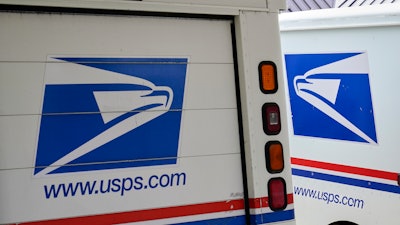 In this file photo mail delivery vehicles are parked outside a post office in Boys Town, Nebraska.