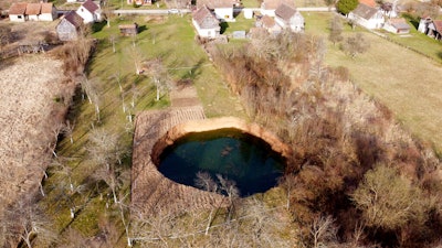 This aerial photo shows a sinkhole in the village of Mececani, central Croatia, Thursday, March 4, 2021. A central Croatian region about 40 kilometers (25 miles) southwest of the capital Zagreb is pocked with round holes of all sizes, which appeared after December's 6.4-magnitude quake that killed seven people and caused widespread destruction. Scientists have been flocking to Mecencani and other villages in the sparsely-inhabited region for observation and study.