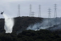 A helicopter drops water near power lines and electrical towers while working at a fire on San Bruno Mountain near Brisbane, Calif., Oct. 10, 2019.