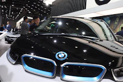 In this file photo, a worker cleans an electric vehicle at the BMW booth during the Auto Shanghai show.