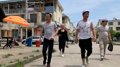 Residents of the Hui Muslim ethnic minority walk in a neighborhood near an OFILM factory in Nanchang, China, June 5, 2019.