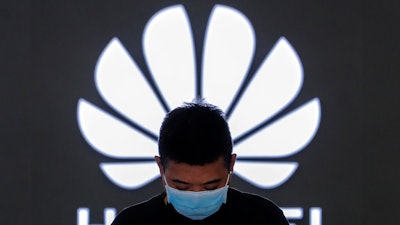 In this file photo, an employee wearing a face mask stands inside a Huawei flagship store in Beijing.