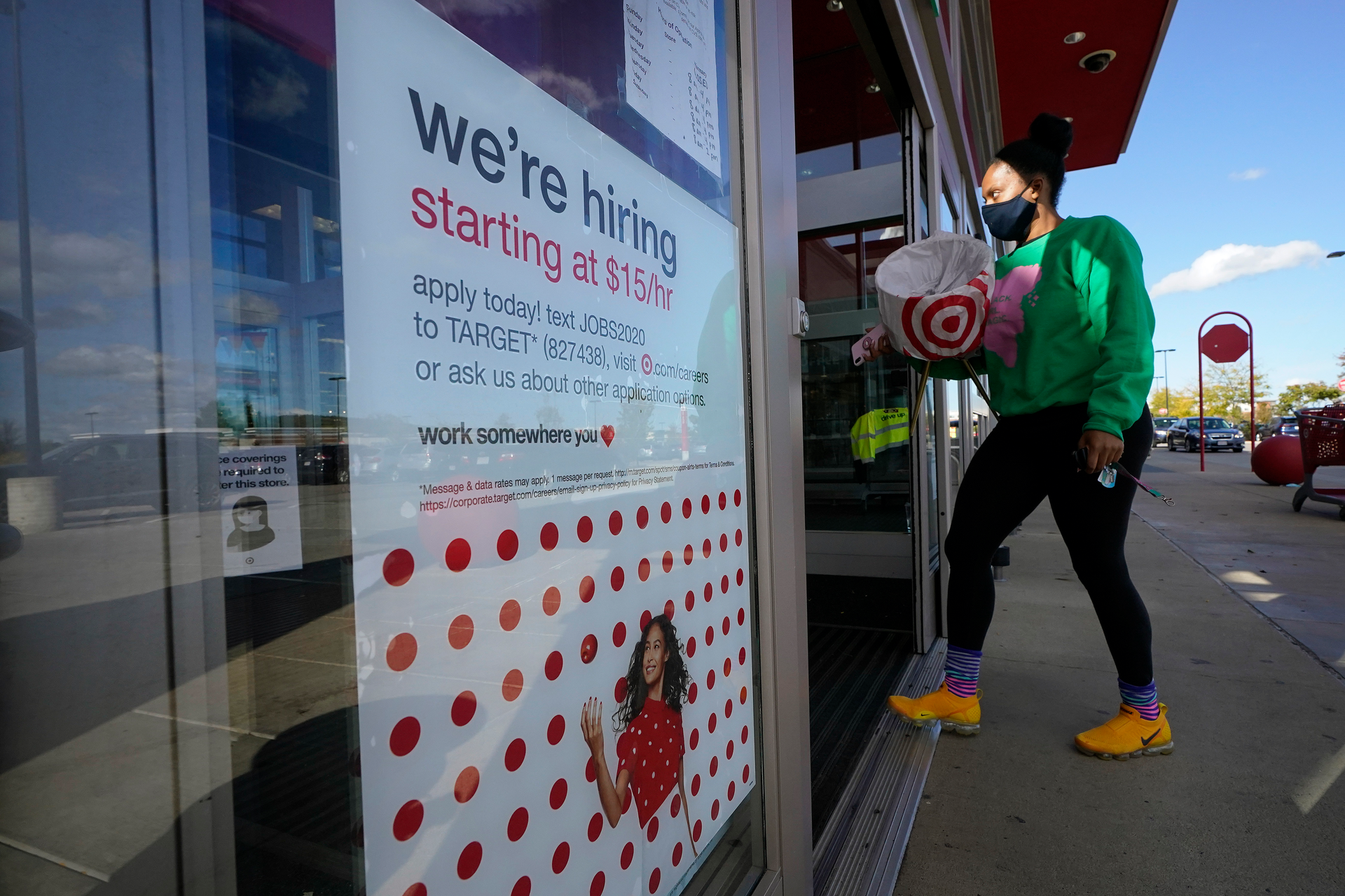 In this file photo, a passerby walks past a hiring sign while entering a Target store in Westwood, MA.
