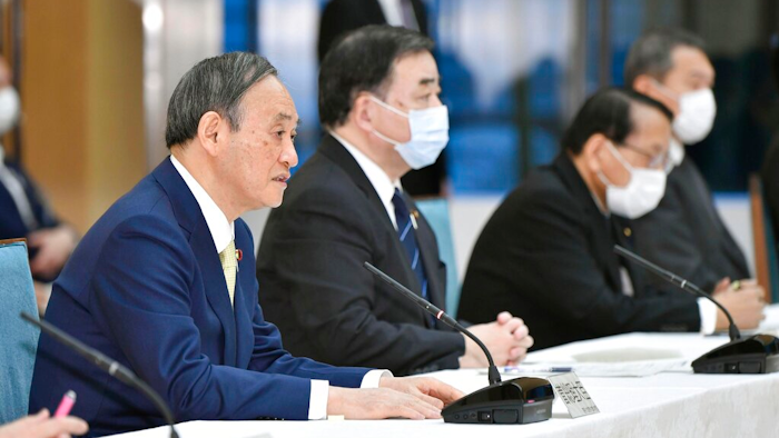 Japanese Prime Minister Yoshihide Suga, left, at a cabinet meeting at his official residence in Tokyo, April 12, 2021.