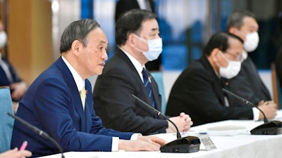 Japanese Prime Minister Yoshihide Suga, left, at a cabinet meeting at his official residence in Tokyo, April 12, 2021.