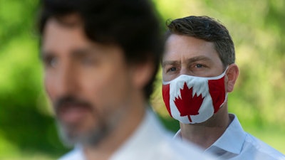 Liberal Member of Parliament William Amos wears a Canadian flag mask as Prime Minister Justin Trudeau speaks during a news conference in Chelsea, Quebec, June 19, 2020.