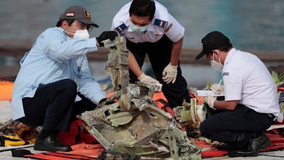 Investigators inspect a pieces of Sriwijaya Air flight SJ-182 retrieved from the Java Sea, Tanjung Priok Port, Jakarta, Jan. 21, 2021.
