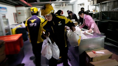 Meituan delivery workers prepare orders in Beijing, March 1, 2016.