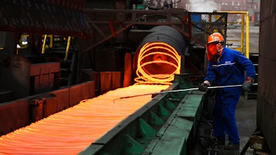 A worker manipulates coils of steel at Xiwang Special Steel, Zouping County, China, March 5, 2018.