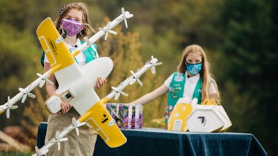Girl Scouts Alice Goerlich, right, and Gracie Walker pose with a Wing delivery drone in Christiansburg, Va., April 14, 2021.