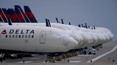 In this May 14, 2020 file photo, several dozen mothballed Delta Air Lines jets are parked on a closed runway at Kansas City International Airport in Kansas City, Mo. Delta Air Lines says it lost $1.2 billion in the first quarter, but the airline thinks it can by profitable by late summer unless there's a resurgence of COVID-19. Delta reported the results on Thursday, April 15, 2021.