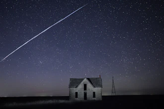 Long-exposure photo of a string of SpaceX Starlink satellites over an old stone house near Florence, Kan., May 6, 2021.