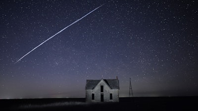 Long-exposure photo of a string of SpaceX Starlink satellites over an old stone house near Florence, Kan., May 6, 2021.