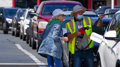 A customer pumps gas as other wait in line at a Costco in Charlotte, N.C., May 11, 2021.