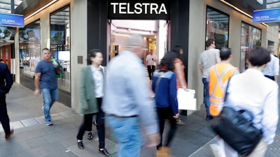 Pedestrians walk pasy a Telstra store in Sydney, May 13, 2021.