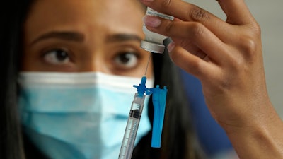Licensed practical nurse Yokasta Castro draws a Moderna COVID-19 vaccine into a syringe at a mass vaccination clinic, Gillette Stadium, Foxborough, Mass., May 19, 2021.