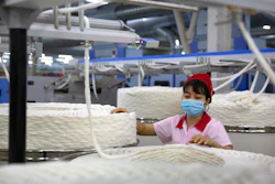 A worker watches as a machine processes cotton yarn at a Huafu Fashion plant, Aksu, China, April 20, 2021.