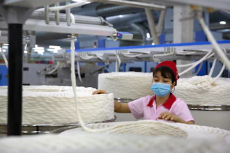 A worker watches as a machine processes cotton yarn at a Huafu Fashion plant, Aksu, China, April 20, 2021.