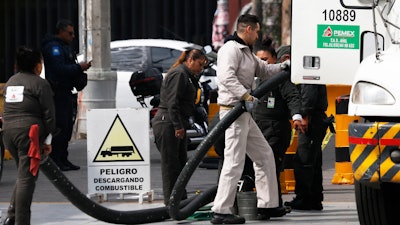 In this file photo, workers discharge gas from a truck to supply a gas station with fuel in the Iztapalapa area of Mexico City.