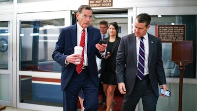 Sen. John Barrasso, R-Wyo., left, and Sen. Todd Young, R-Ind., rush to the chamber for votes at the Capitol in Washington, May 27, 2021.