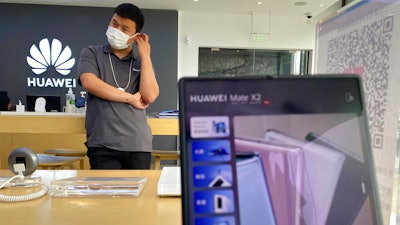 A worker waits for customers inside a Huawei store in Beijing, June 2, 2021.