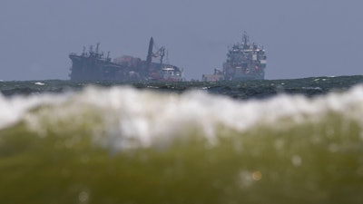 The MV X-Press Pearl, left, is pulled by a navel vessel at Kapungoda, where it is anchored off Colombo port, Sri Lanka, June 2, 2021.