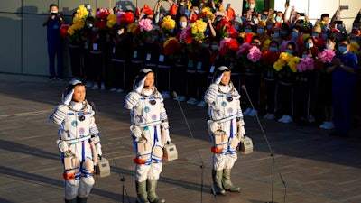 Chinese astronauts, from left, Tang Hongbo, Nie Haisheng, and Liu Boming salute as they prepare to board for liftoff at the Jiuquan Satellite Launch Center, June 17, 2021.