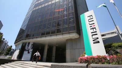 In this May 14, 2018, file photo, a man walks in front of Nishiazabu headquarters of Fujifilm Holdings Corporation in Tokyo.
