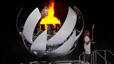 Naomi Osaka stands beside the Olympic flame after lighting it during the opening ceremony, July 23, 2021, Tokyo.