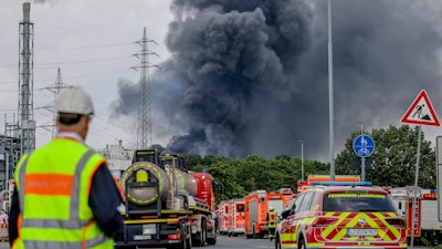 Emergency vehicles near an access road to the Chempark, over which a dark cloud of smoke is rising, Leverkusen, Germany, July 27, 2021.