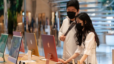 Customers view iMac computers in an Apple store, New York, May 21, 2021.