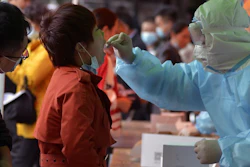 Medical staff takes a swab from a woman as residents line up for a COVID-19 test near a residential area in Qingdao, China, Oct. 12, 2020.