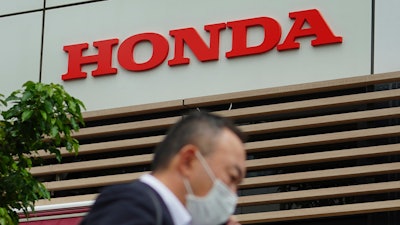 A man wearing a protective mask to help curb the spread of the coronavirus walks past the logo of Honda Motor Company in Tokyo, May 13, 2021.
