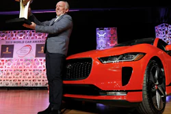 Jaguar Design Director Ian Callum raises the World Car of the Year trophy that was awarded to the Jaguar I-Pace, right, at the 2019 New York International Auto Show, April 17, 2019.
