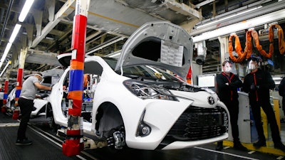 In this April 28, 2020 photo, an employee wearing a face mask works on a Yaris car at the Toyota car factory in Onnaing, northern France.