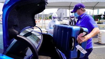 An Uber driver loads luggage at Los Angeles International Airport, Aug. 20, 2020.