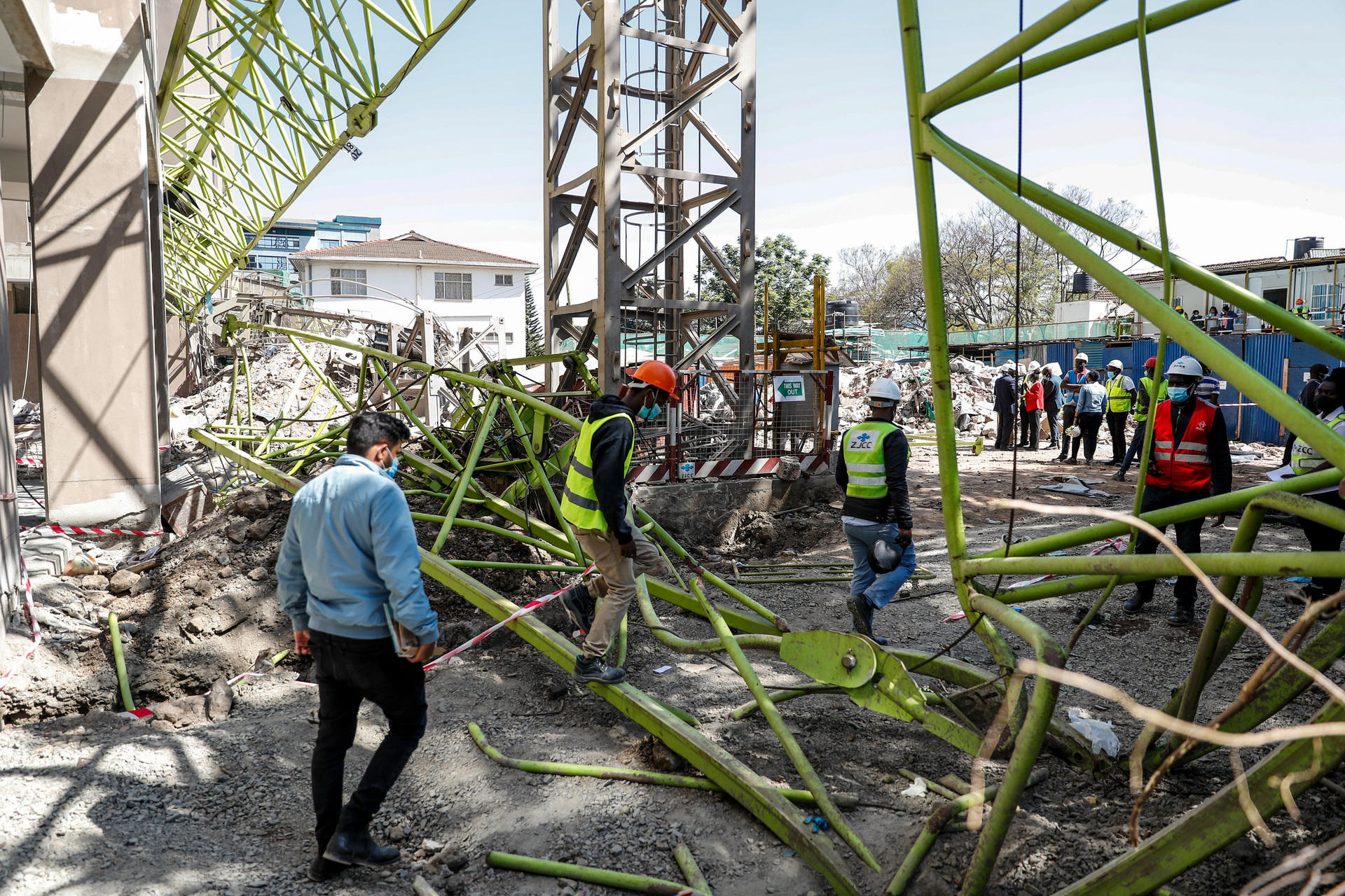 Construction workers observe the wreckage after a crane collapsed at a construction project to build a 14-storey student hostel in Nairobi, Kenya Thursday, Aug. 26, 2021. Police in Kenya's capital say nine people are dead, including two Chinese engineers, after the crane collapsed at the site being supervised by a Chinese construction firm.